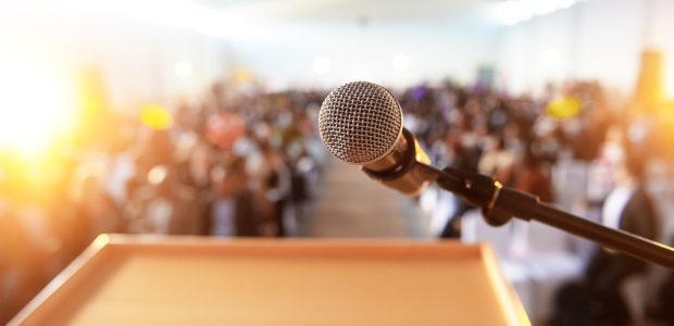 Microphone in front of podium with crowd in the background